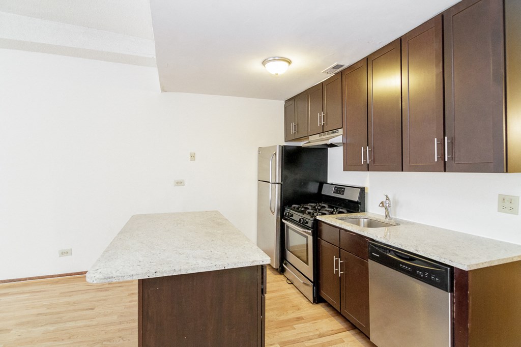 an empty kitchen with stainless steel appliances and marble counter tops