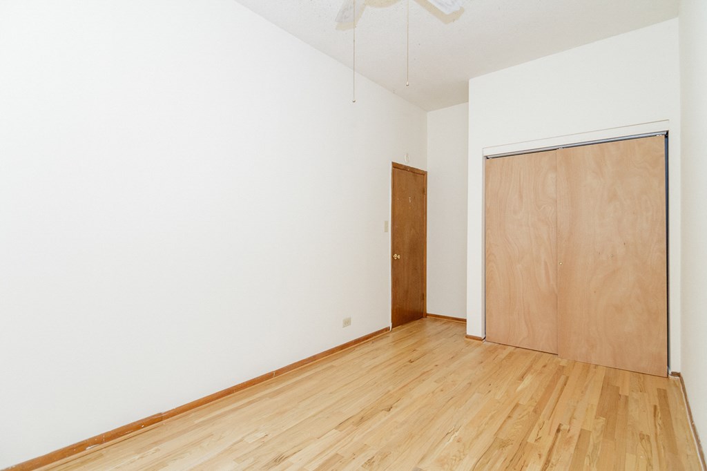 an empty room with white walls and wooden floors and a wooden door