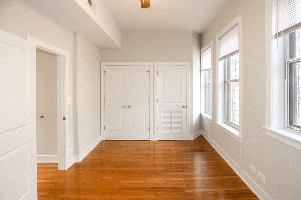 an empty room with wooden floors and white doors and windows