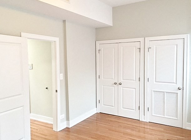 an empty room with white closet doors and a wood floor