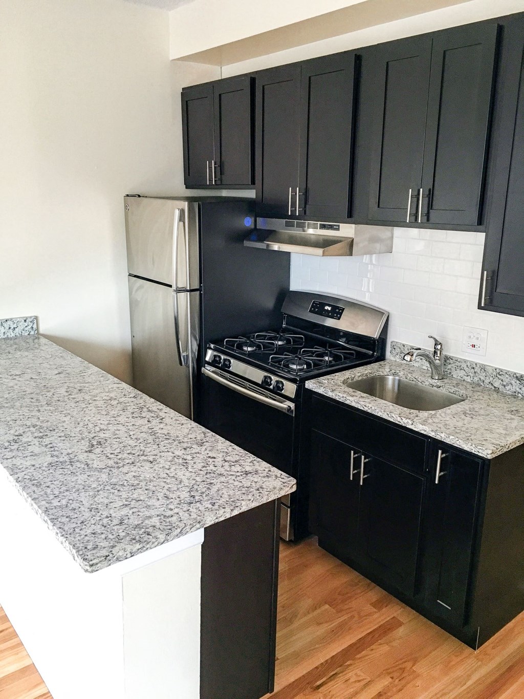 a kitchen with black cabinets and stainless steel appliances and a sink