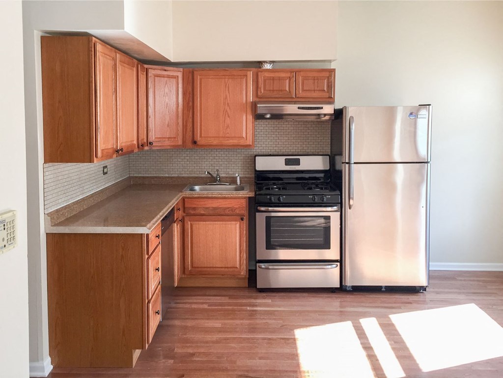 an empty kitchen with wooden cabinets and stainless steel appliances