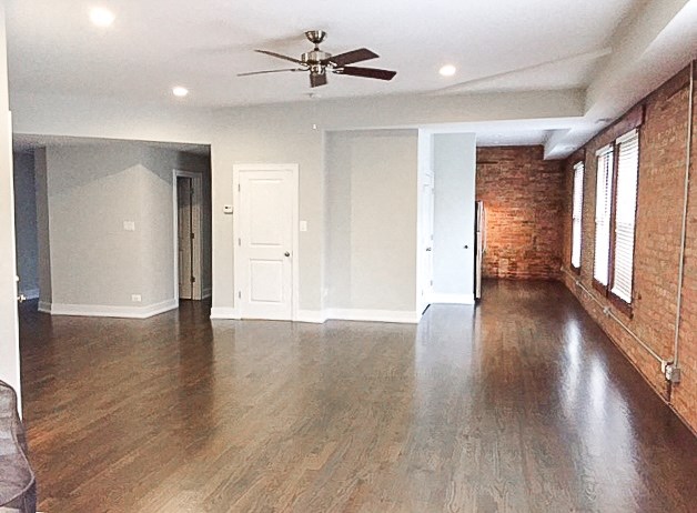 an empty living room with wood floors and a ceiling fan