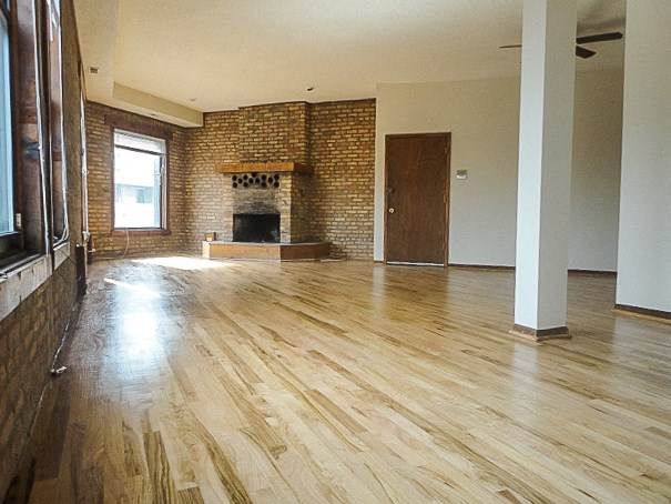 an empty living room with a fireplace and wooden floors