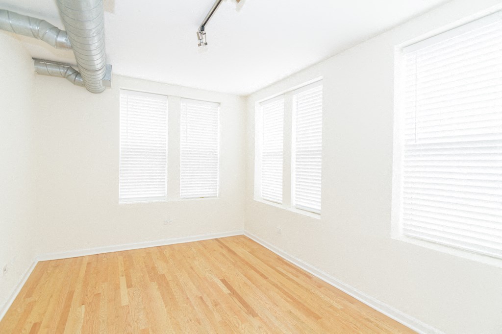 an empty room with white shutters and a wood floor
