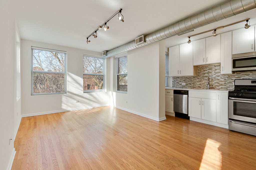 an open kitchen and living room with wood floors and white cabinets