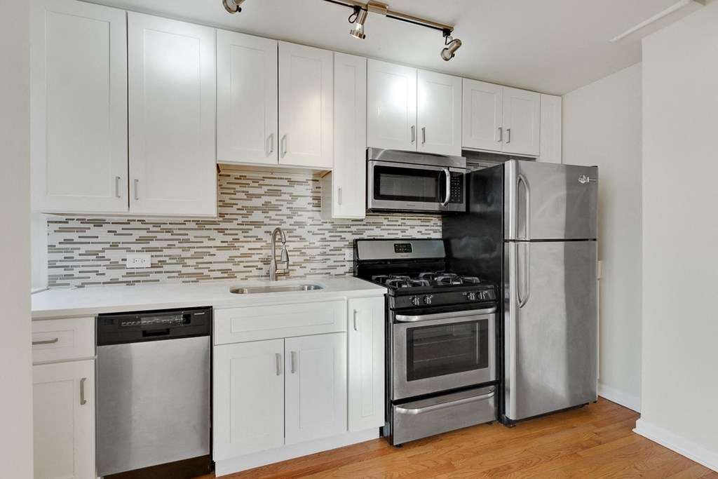 a kitchen with white cabinets and stainless steel appliances