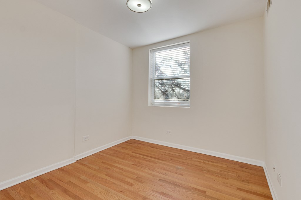 an empty room with wood flooring and a window