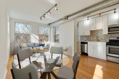 a living room with a table and chairs and a kitchen with a large window
