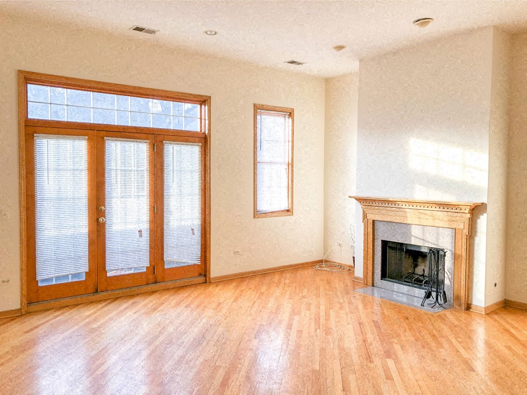 an empty living room with a fireplace and wooden floors