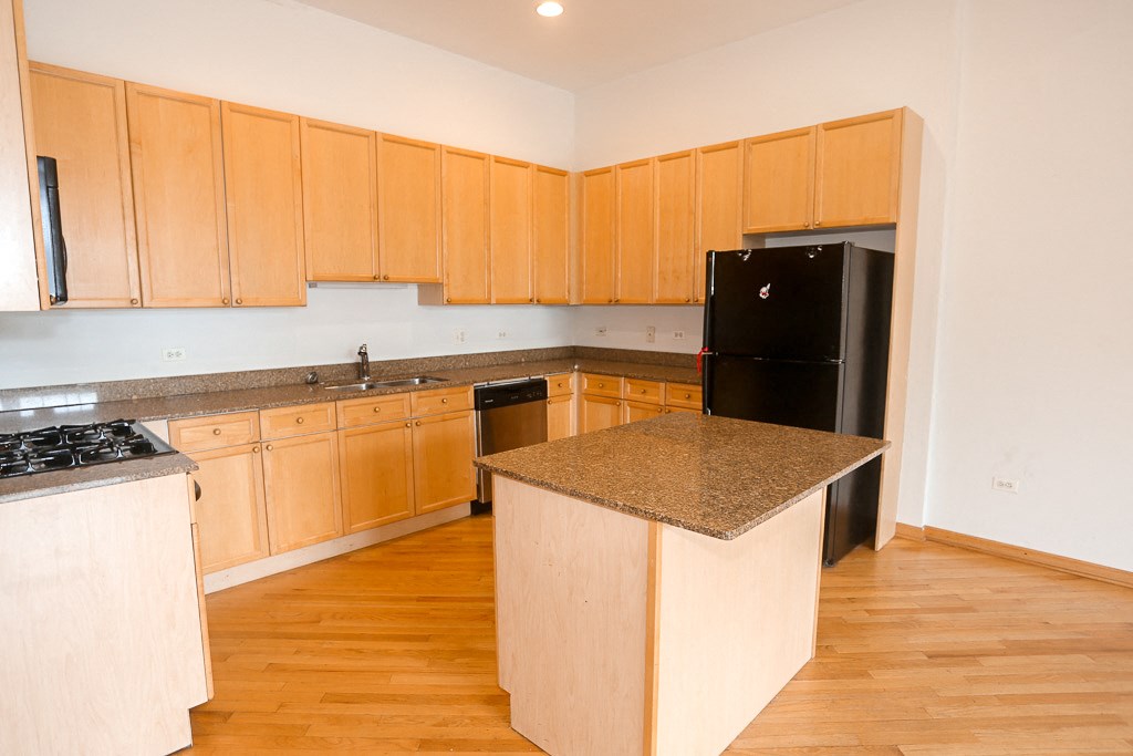 a kitchen with wooden cabinets and a black refrigerator