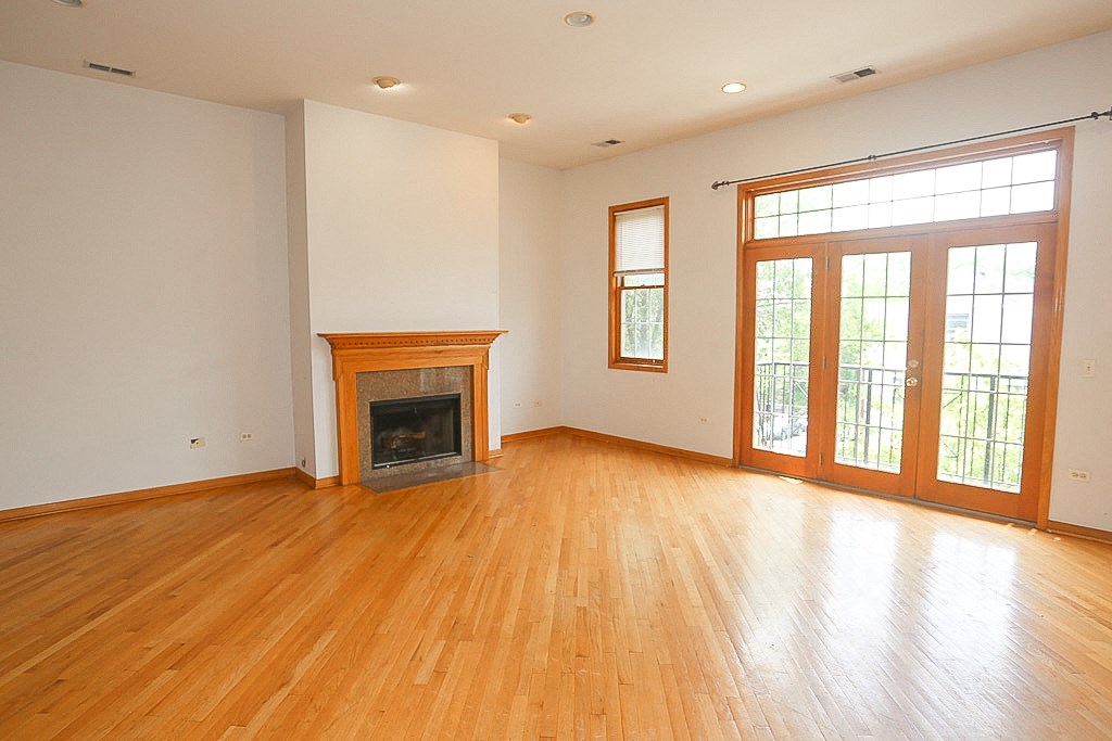 an empty living room with wood floors and a fireplace