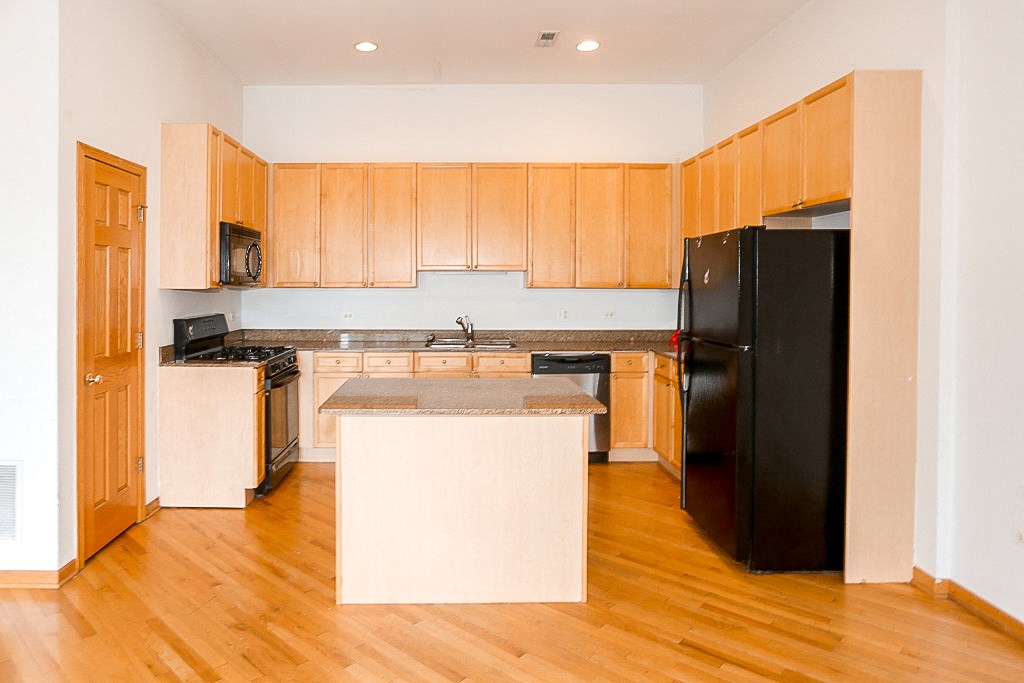 a kitchen with wooden cabinets and a black refrigerator
