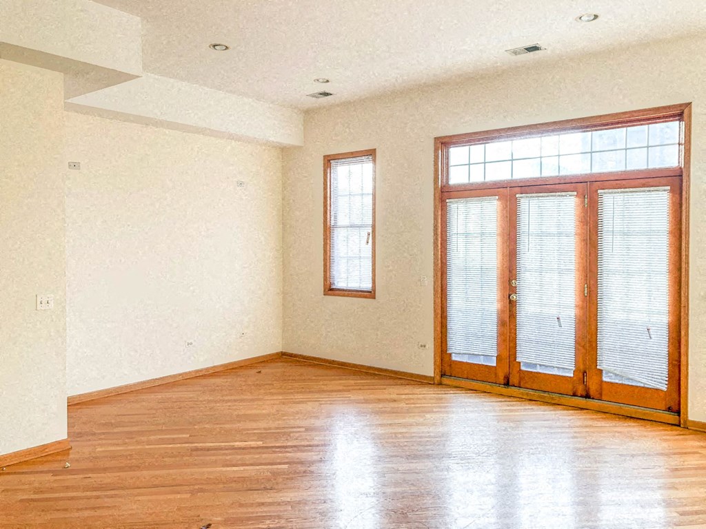 an empty living room with wood floors and a large window