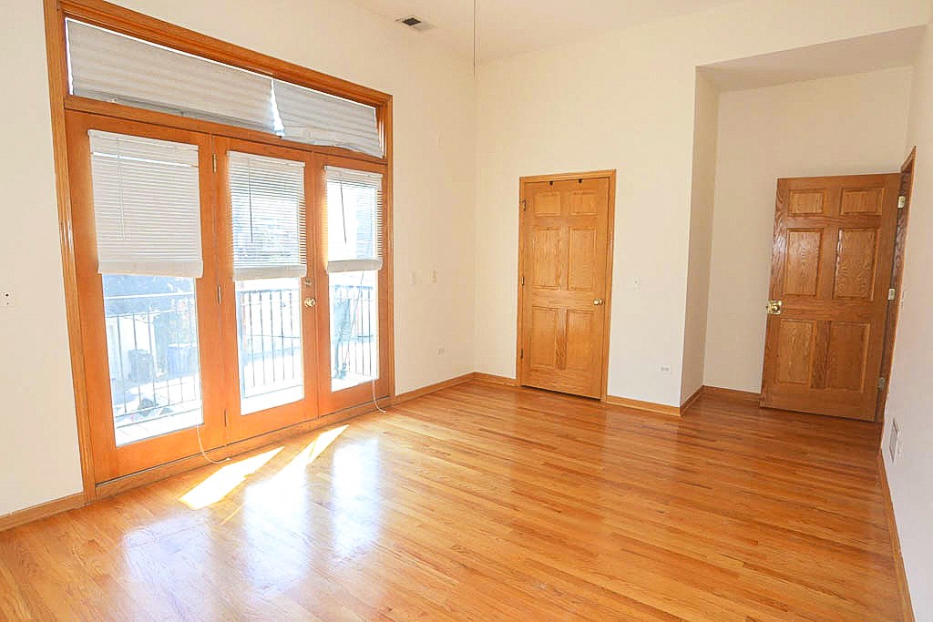 an empty living room with wooden floors and doors