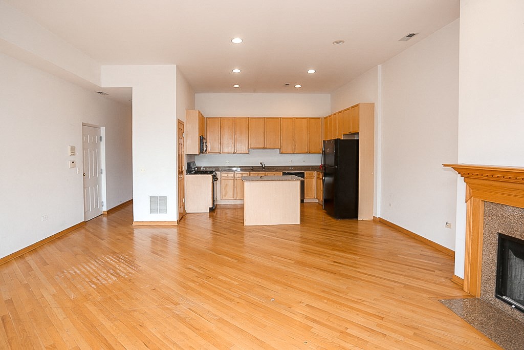 an empty living room and kitchen with wood flooring