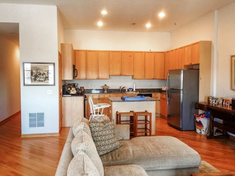 a living room with a couch and a kitchen with a refrigerator