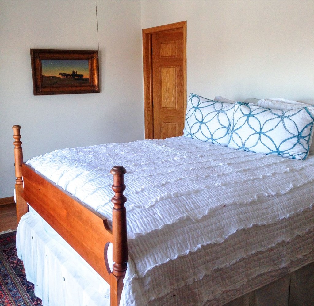 a bedroom with a bed with a white comforter