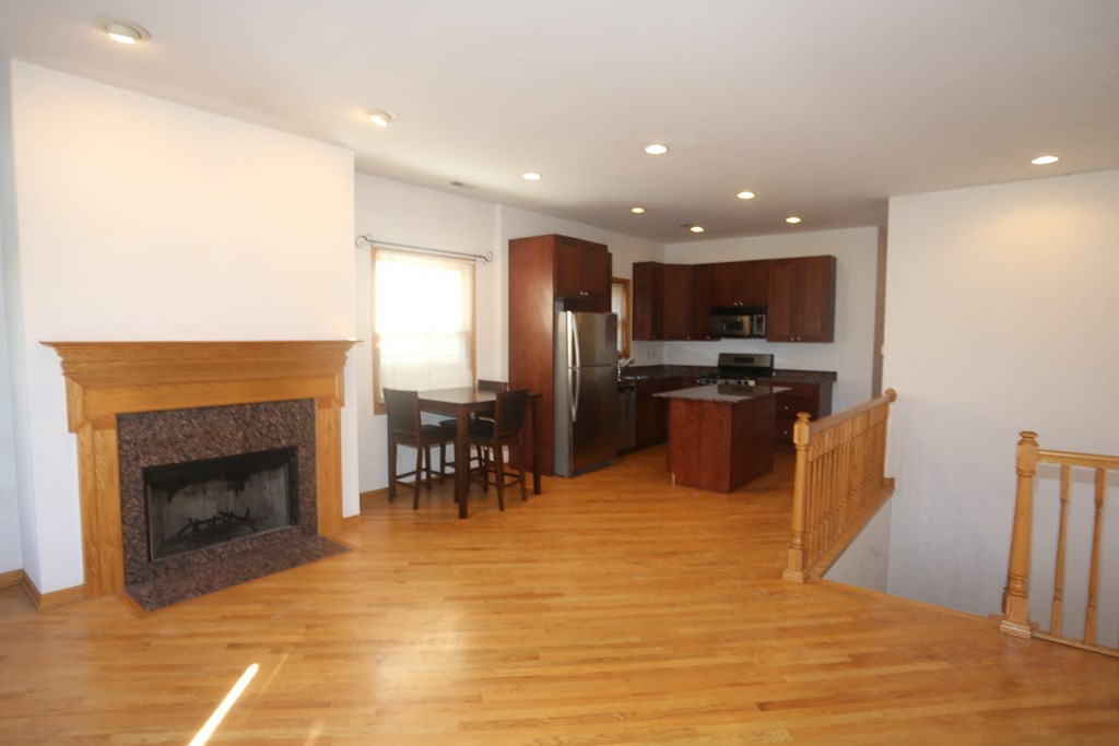 an empty living room with a fireplace and a kitchen
