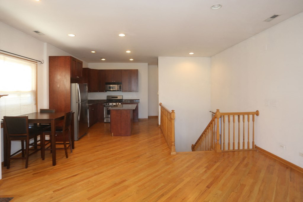 an empty living room with a kitchen and a staircase