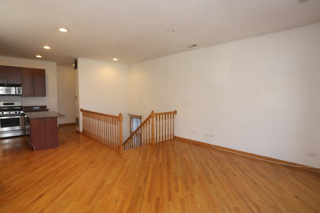 an empty living room with wood floors and a staircase