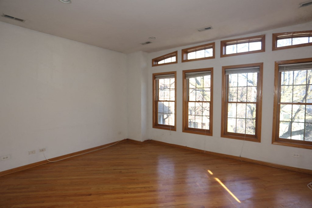 an empty living room with wooden floors and windows