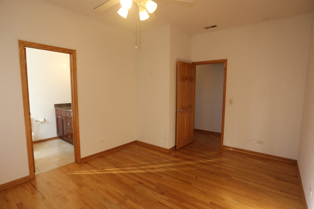 an empty living room with wooden floors and a door to a bathroom