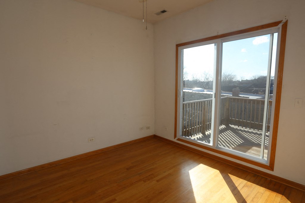 an empty living room with a large window and wooden floors