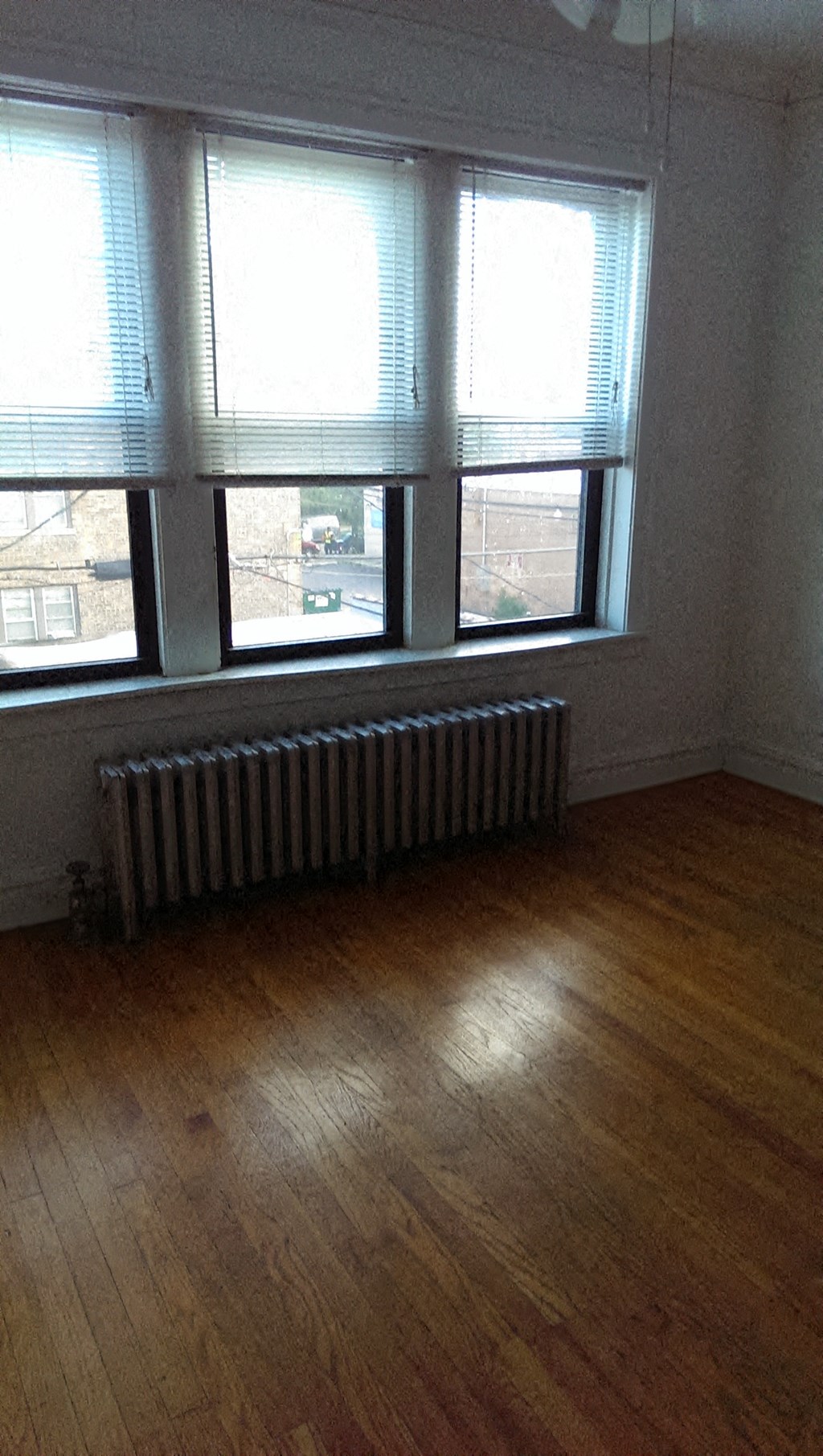 a living room with a wood floor and three windows