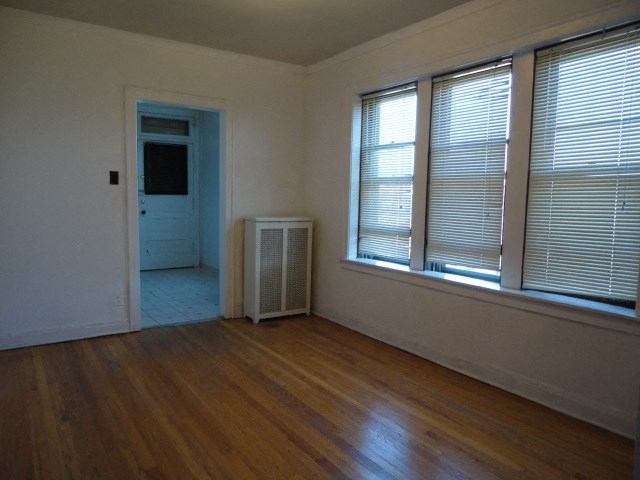 the living room of a house with a wood floor and three windows
