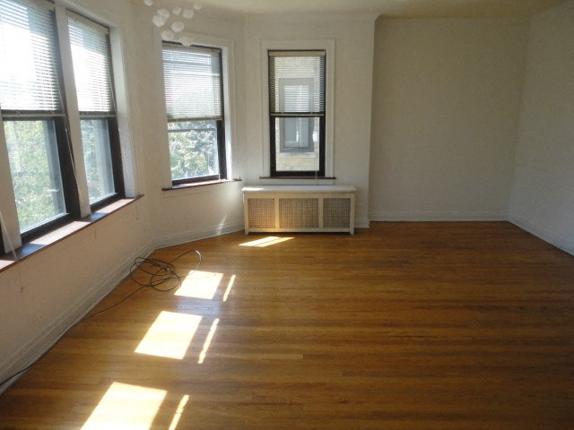 an empty living room with a wood floor and three windows
