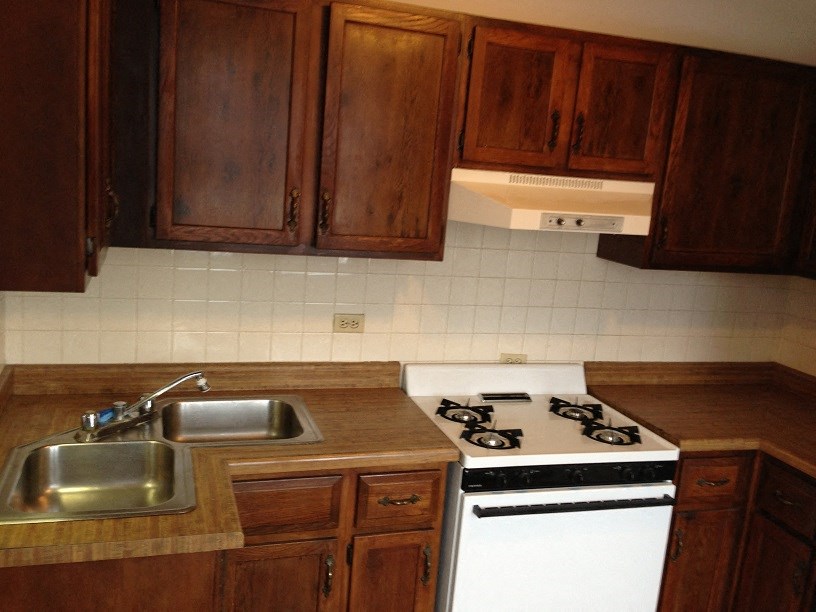 a kitchen with a stove and a sink and wooden cabinets