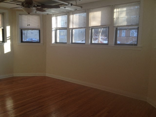 an empty living room with a wooden floor and windows