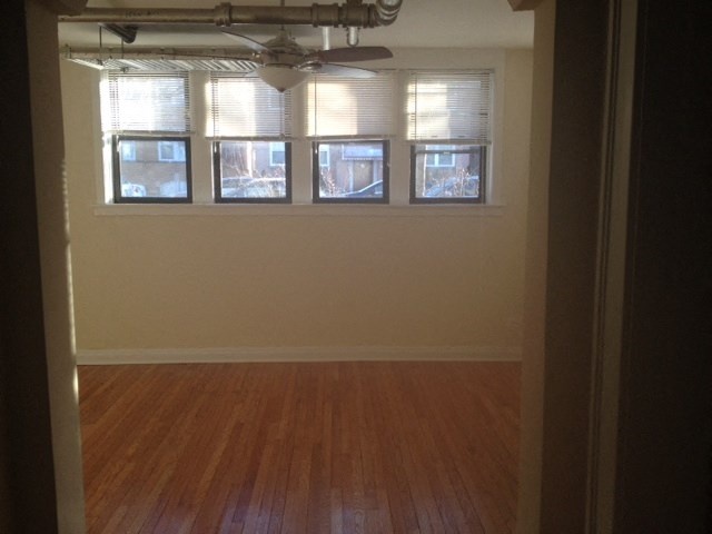 an empty living room with a wood floor and windows