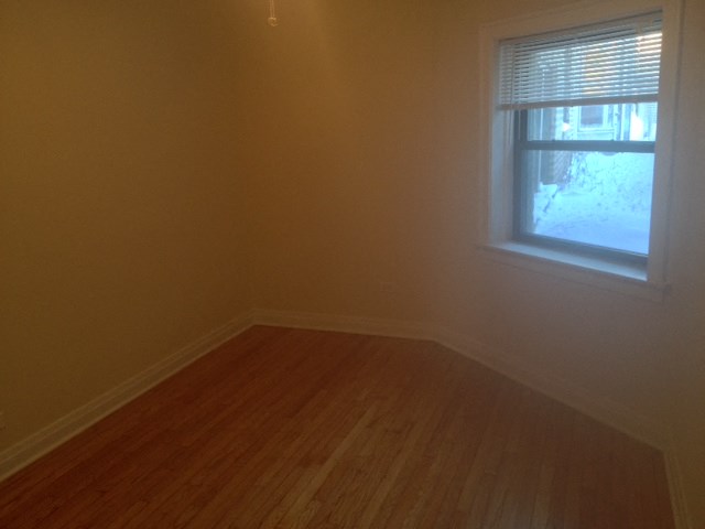an empty room with a window and wooden floors