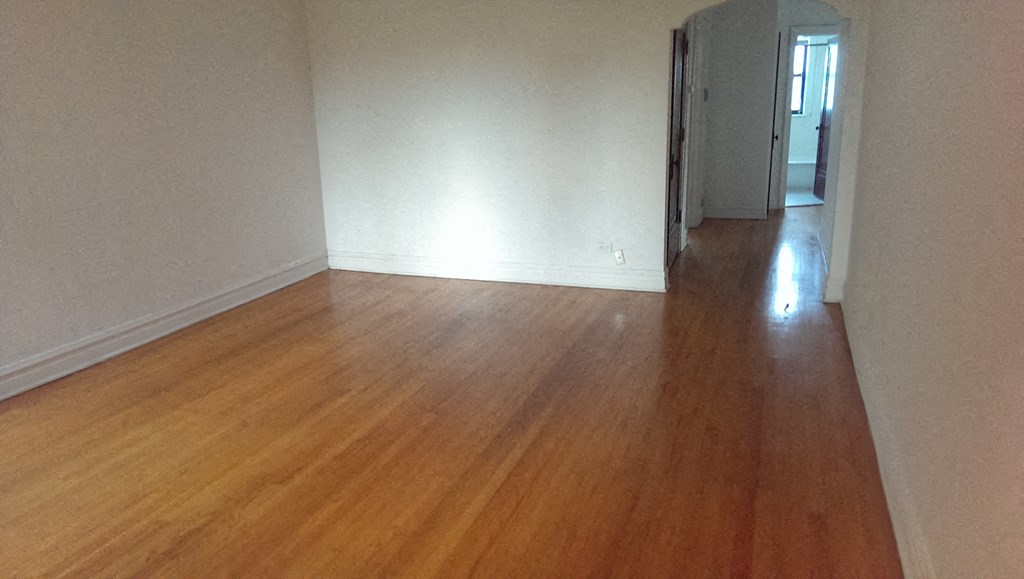an empty living room with wooden floors and white walls