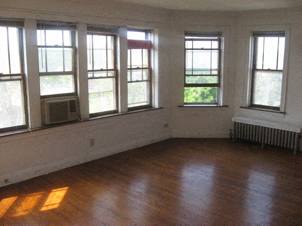an empty room with a wood floor and many windows