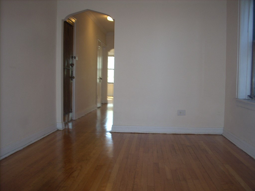 an empty living room with wooden floors and white walls
