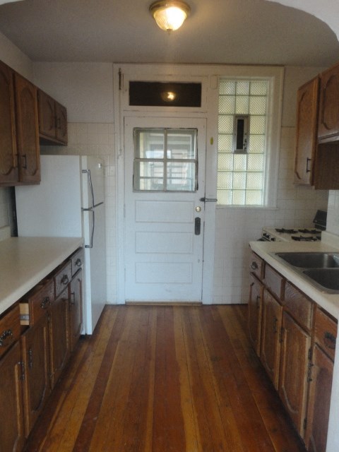 an empty kitchen with wooden floors and a white door