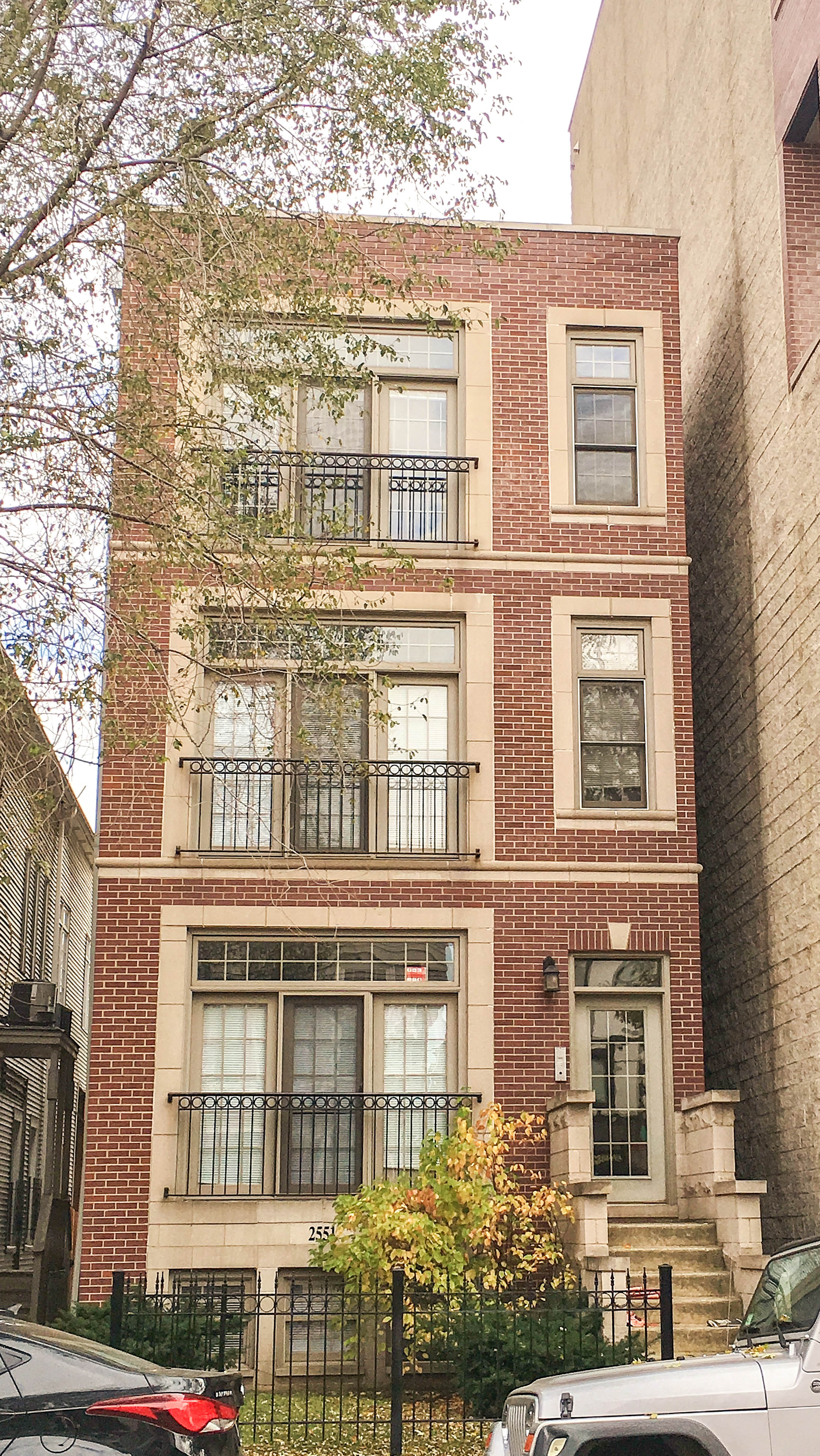 a red brick building with many windows and a black fence