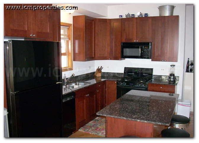 a kitchen with wooden cabinets and a black refrigerator