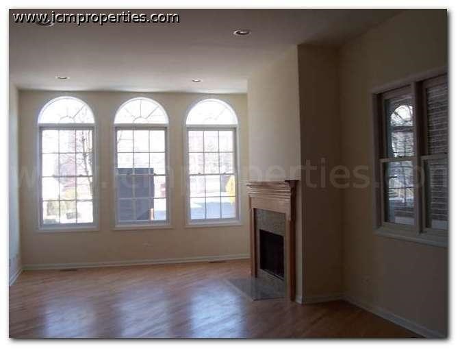 a empty living room with three windows and a fireplace