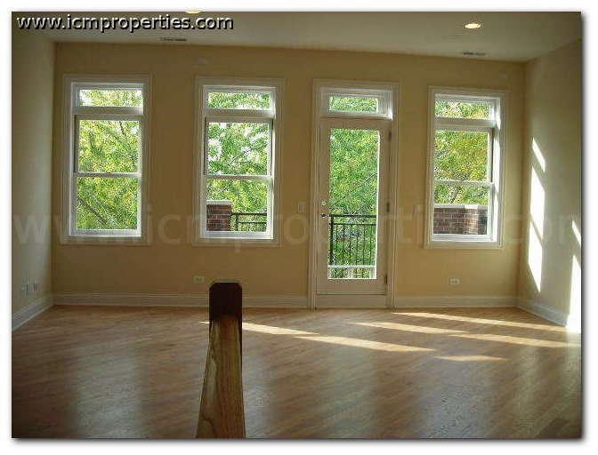 an empty living room with a wood floor and windows