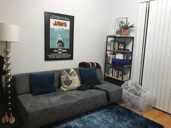 a living room with a couch and a movie poster on the wall