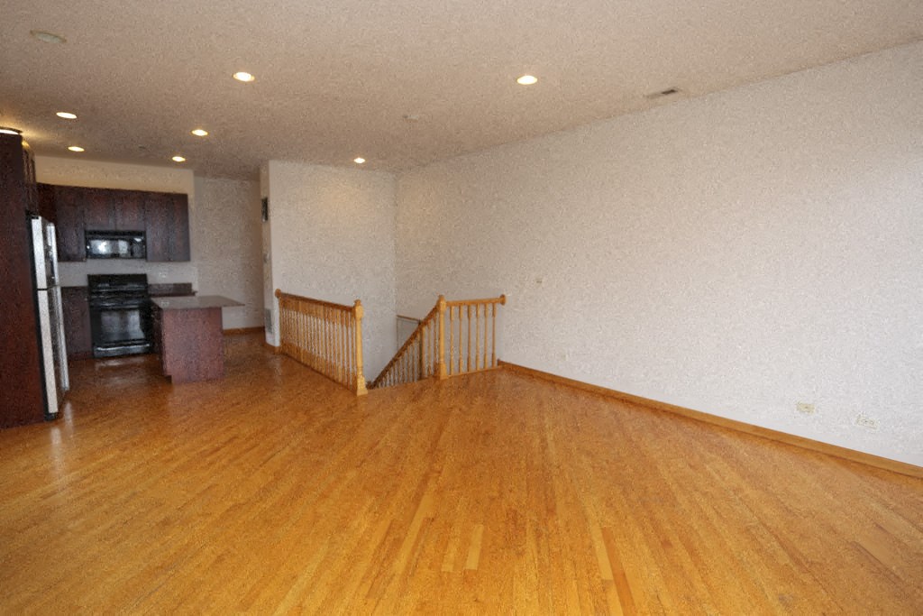 an empty living room with a hard wood floor and a staircase