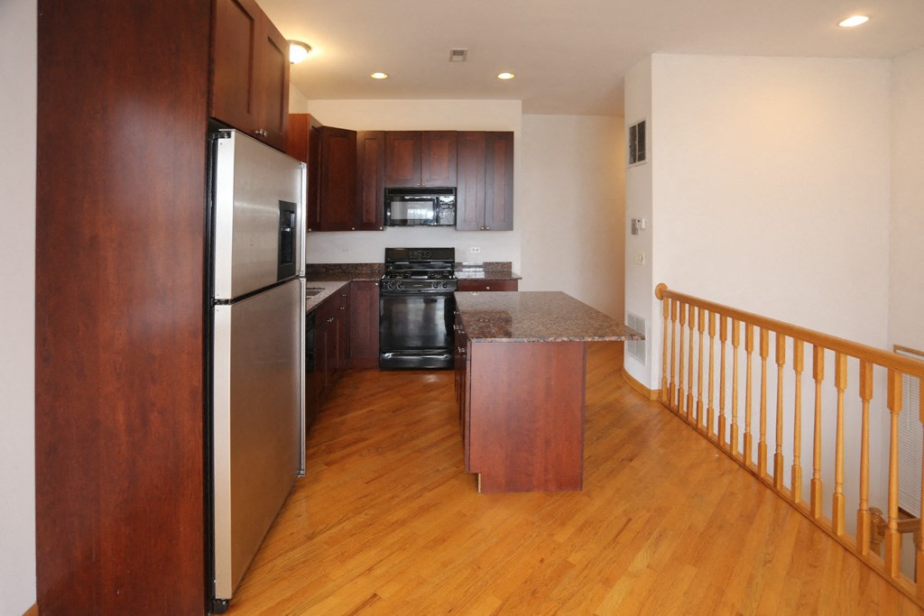 a kitchen with wood floors and stainless steel appliances