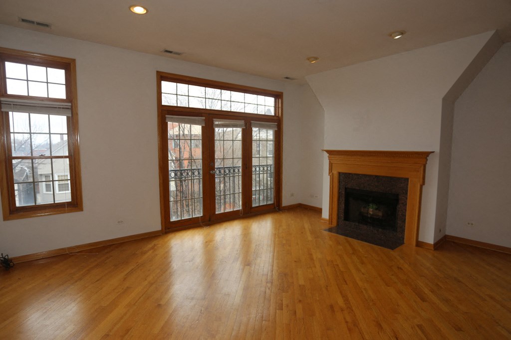 an empty living room with wood floors and a fireplace