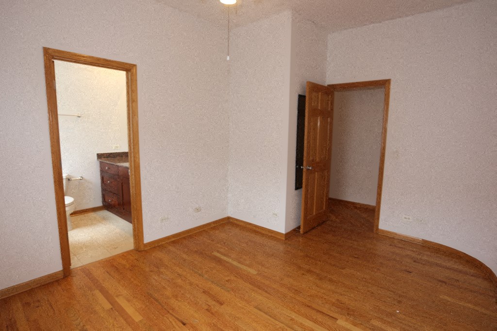an empty room with wooden floors and a door to a bathroom