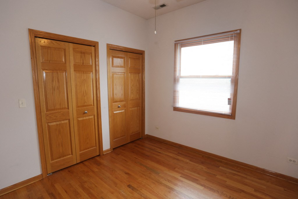 an empty room with wooden floors and a window and two doors