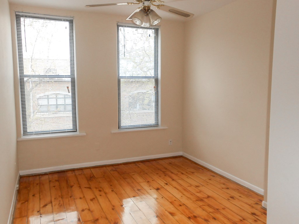 an empty living room with wooden floors and a ceiling fan